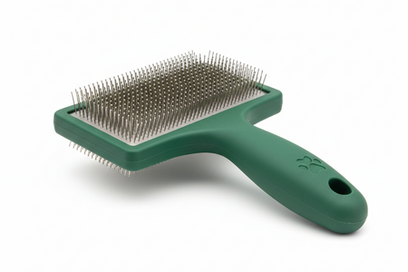 Green pet grooming brush on a white background